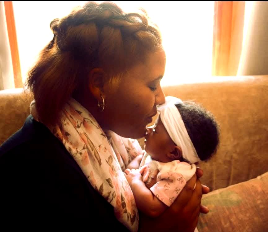 A mother tenderly kisses her newborn baby